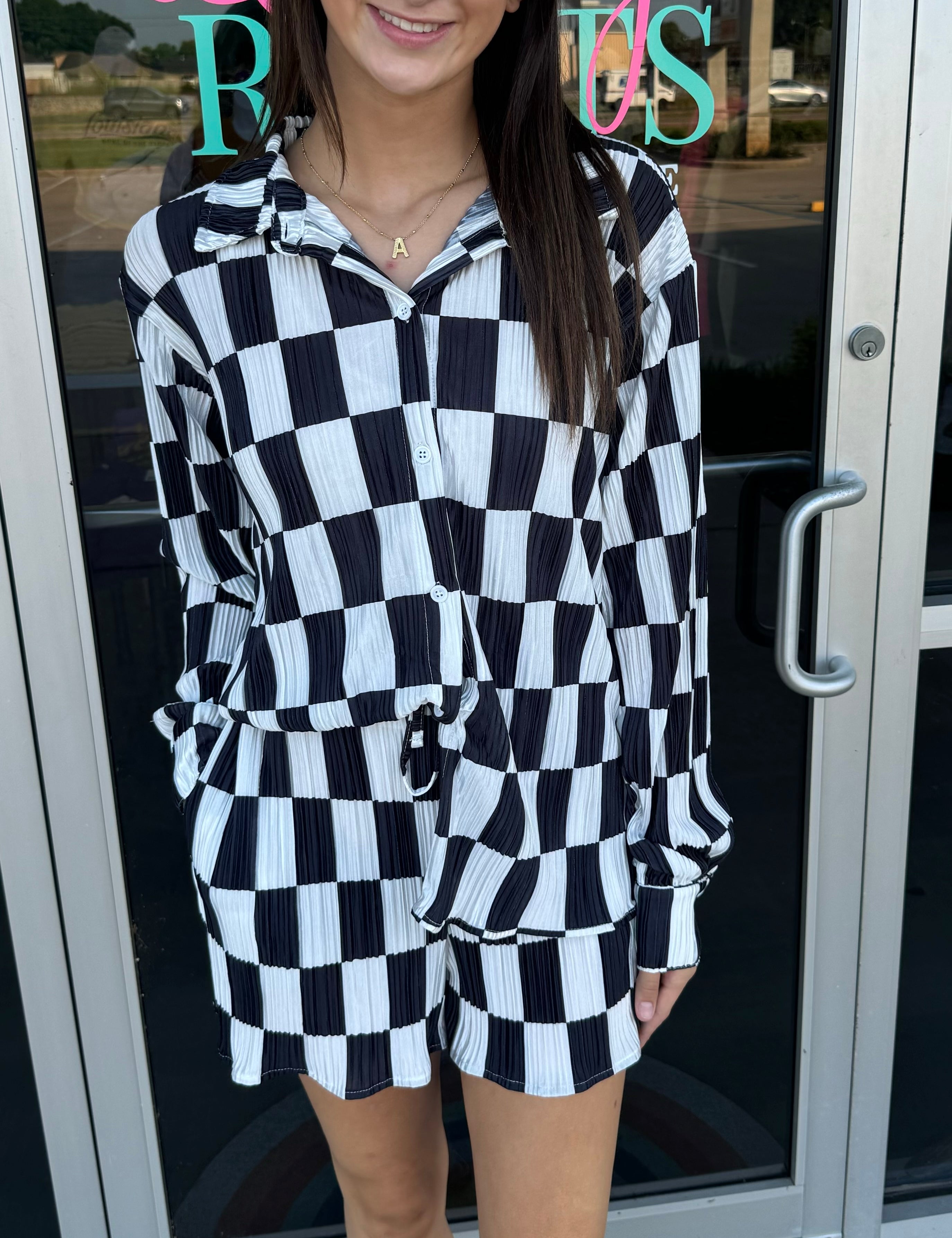 Woman wearing a black and white checkered outfit standing in front of a store entrance.
