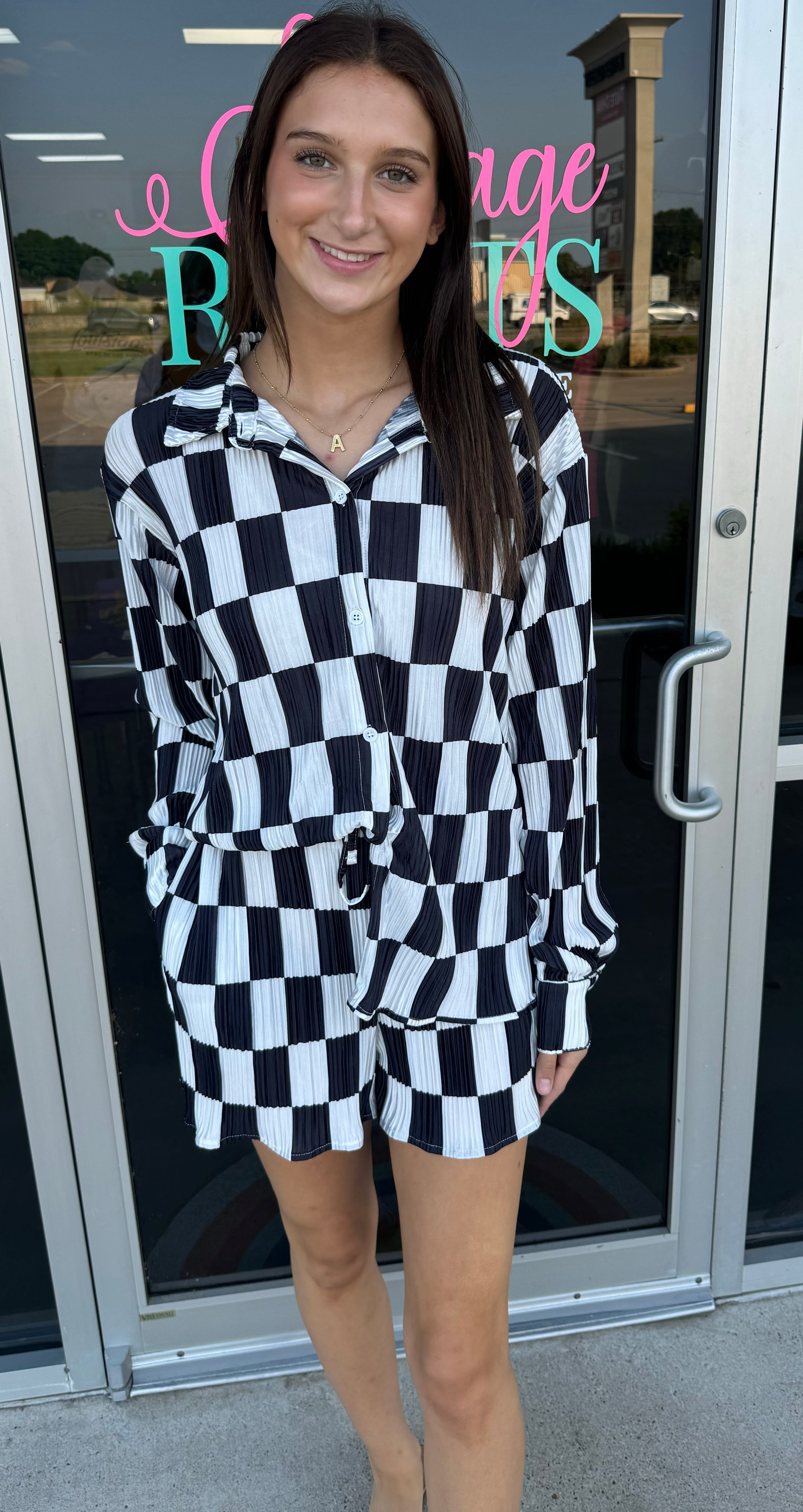 Woman wearing a black and white checkered outfit standing in front of a store entrance.
