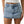 Person wearing a light blue denim skirt on a neutral background
