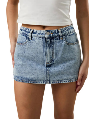 Person wearing a light blue denim skirt on a neutral background
