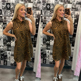 Woman wearing a zebra print dress in front of a patterned wall.
