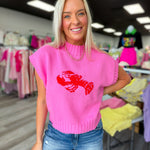 Woman wearing a pink sweater with a red lobster design in a store setting.