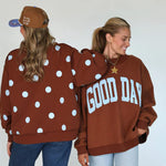 Two people wearing brown sweatshirts with polka dots and 'GOOD DAY' text, standing back-to-back against a white background.