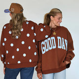 Two people wearing brown sweatshirts with polka dots and 'GOOD DAY' text, standing back-to-back against a white background.