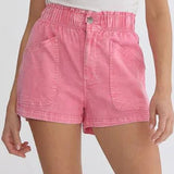 Woman wearing pink shorts and beige knee-high boots on a white background