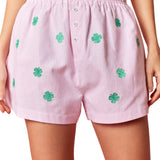 Pink shorts with green four-leaf clover patterns on a pink background