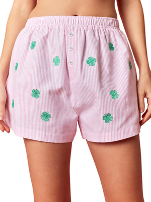 Pink shorts with green four-leaf clover patterns on a pink background